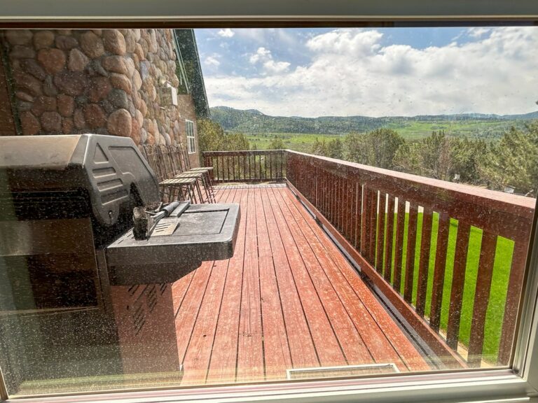 Large picture window cleaned streak-free, looking out over a deck and green hills